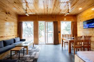 un soggiorno con un divano e un tavolo di Nirmaya Resort a Kanatal
