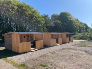 a group of wooden buildings sitting in a yard at Hærvejshallen Hytte 1 in Bække