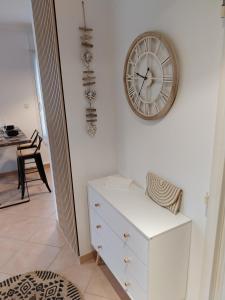 a clock on a wall next to a white dresser at Cap Marine in Cavalaire-sur-Mer