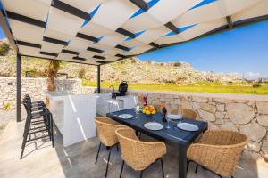 a patio with a table and chairs under a roof at Villa 13 Zendo in Kolymbia