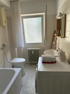 Un baño blanco con lavabo e inodoro. en Living Lu - cosy Apartment one - Netflix - Mannheim - BASF - 1 Zimmer, en Ludwigshafen am Rhein 3 fotos más