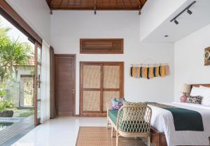 a bedroom with a bed and a chair at Dijero at Umah Bali in Ubud +30 photos