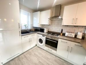 a kitchen with white cabinets and a dishwasher at Ruby Place by Blue Skies Stays in Hartlepool