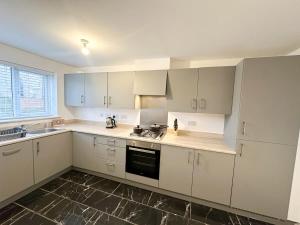 a kitchen with white cabinets and a stove top oven at Curlew Place by Blue Skies Stays in Stockton-on-Tees