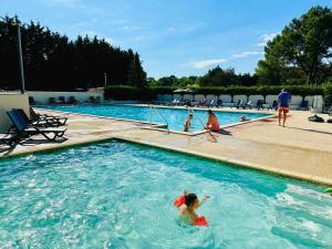 a group of people swimming in a swimming pool at O'PARADIS - Mobil-home au calme, clim, BBQ & piscine in Les Mathes