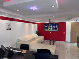 a living room with a couch and a tv on a wall at Nogixa Lodge in Umzimkulu