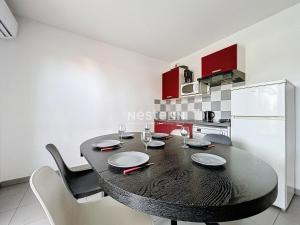een keuken met een zwarte tafel en stoelen en een koelkast bij 3313-Appartement 8 couchages avec piscine in Argelès-sur-Mer