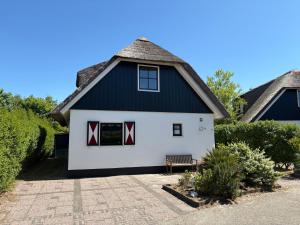 a white house with a thatched roof at Buitenplaats 105 in Callantsoog