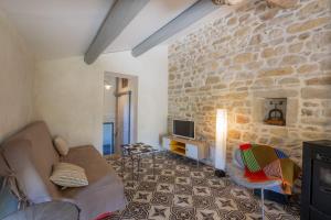 a living room with a couch and a stone wall at Gîte Figuier au Mas Dujau in Saint-Sauveur-de-Cruzières