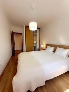 a bedroom with a large white bed with a light at Elegant Getaway II - Lisbon- two bedroom apartment in Montijo- 10 mints from the beach in Atalaia +2 photos