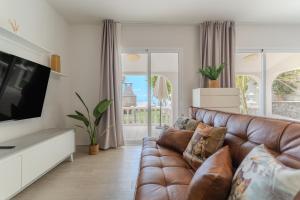 a living room with a brown leather couch and a television at Villa Blanca in Callao Salvaje