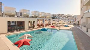 two people swimming in a swimming pool on a building at Hotel Indigo Albufeira by IHG in Albufeira