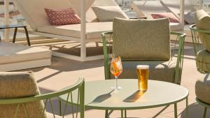 a table with a glass of wine and chairs at Hotel Indigo Albufeira by IHG in Albufeira