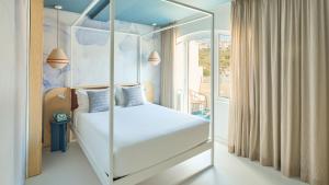 a bedroom with a white canopy bed with a window at Hotel Indigo Albufeira by IHG in Albufeira