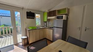 Camping les Mancellieres في Avrillé: مطبخ مع طاولة وثلاجة