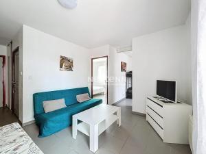 ein Wohnzimmer mit einer blauen Couch und einem Fernseher in der Unterkunft 3304-T3 dans une résidence avec piscine in Argelès-sur-Mer