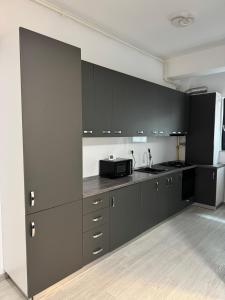 eine Küche mit schwarzen Schränken und einer Mikrowelle in der Unterkunft Blue Apartment in Năvodari