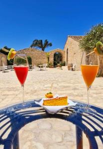 two glasses of wine and a plate of food on a table at Torre Dantona Country Suites in Pozzallo