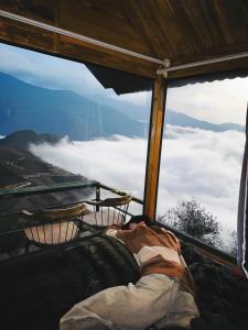 a bed in a room with a view of the clouds at Tà Xùa Retreat Khu Nghỉ Dưỡng in Bắc Yên