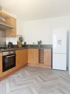 a kitchen with wooden cabinets and a white refrigerator at Alma House by Blue Skies Stays in Hartlepool