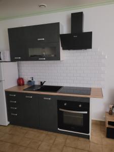a kitchen with black cabinets and a sink at kerNowen in Retiers