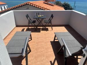 a patio with a table and chairs on a balcony at Gori House in Madalena do Mar