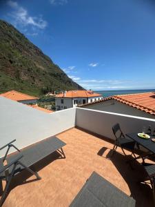 a patio with two chairs and a table on a roof at Gori House in Madalena do Mar