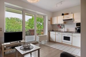 ヴレーメンにあるFerienwohnung Wurster Nordseeküsteの白いキャビネットと大きな窓のあるキッチン