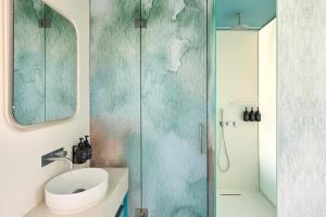 a bathroom with a glass shower with a sink at Hotel Indigo Albufeira by IHG in Albufeira