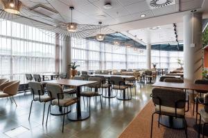 a restaurant with tables and chairs and windows at Scandic Simonkenttä in Helsinki