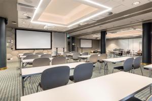 a conference room with tables and chairs and a projection screen at Scandic Simonkenttä in Helsinki