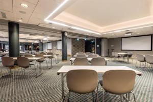 a conference room with tables and chairs and a projection screen at Scandic Simonkenttä in Helsinki