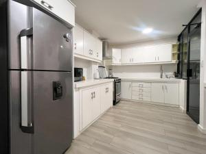 a kitchen with white cabinets and a stainless steel refrigerator at Sky Loft 3 cuadras a la UTPL 5min del centro in Loja +20 photos
