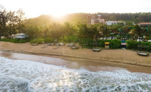 a beach with chairs and palm trees and the ocean at Radisson Resort Phan Thiet in Phan Thiet
