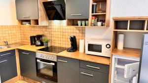 a kitchen with a stove and a microwave at Waldtwin 2 Titisee (W12) + Hochschwarzwald Card in Titisee-Neustadt