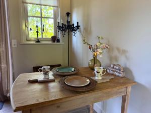a wooden table with plates and cups and a window at Het plekje dat niemand wist in Ederveen +8 photos