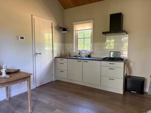 a kitchen with white cabinets and a sink at Het plekje dat niemand wist in Ederveen