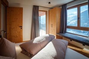a bedroom with a bed and a large window at Lahnerhof Chalets - Mountain view and Sauna inclusive in Lutago