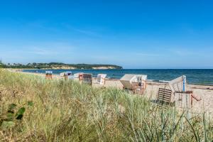 a row of chairs sitting on a beach at Strandtraum Lobbe Fewo 20 bis 4 Personen, auf Anfrage mit Strandkorb in Lobbe