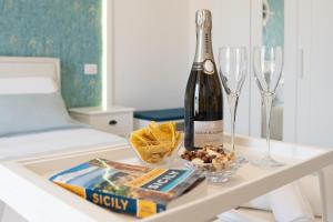 a bottle of wine and wine glasses on a table at Catania Over Time - Tourist Rooms in Catania