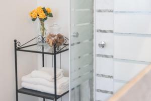 a glass shelf with towels and a vase of flowers at Catania Over Time - Tourist Rooms in Catania