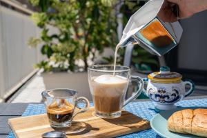 a person pouring coffee into two cups on a table at Catania Over Time - Tourist Rooms in Catania