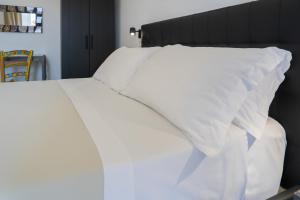 a white bed with white sheets and pillows at Catania Over Time - Tourist Rooms in Catania