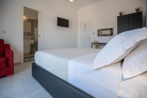 a white bed with white pillows and a red chair at Catania Over Time - Tourist Rooms in Catania