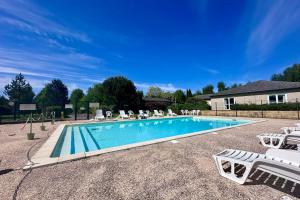 una piscina con sedie a sdraio bianche di Chalet de 4 pers - Lac de Miel à 500m - Beynat - Parking Piscine a Beynat