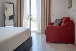 a bedroom with a bed and a red chair at Catania Over Time - Tourist Rooms in Catania