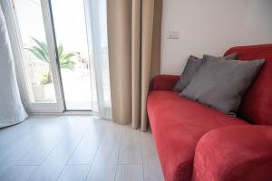 a red couch in a living room with a window at Catania Over Time - Tourist Rooms in Catania