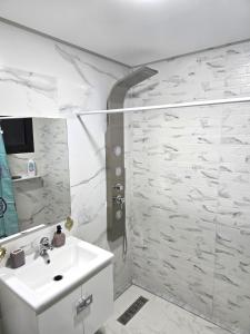 マラケシュにあるRiad Miraleziaの洗面台とシャワー付きの白いバスルーム