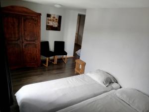 a bedroom with a bed and two chairs and a cabinet at Appartement 1 à 4 pers in Granges-Aumontzey