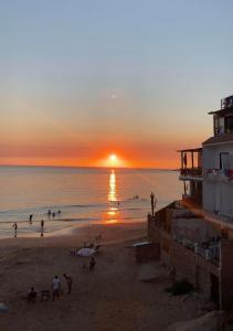 eine Gruppe von Menschen am Strand bei Sonnenuntergang in der Unterkunft Taghazout studio & rooftop in Taghazout